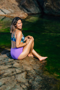 Portrait of woman sitting on rock by sea