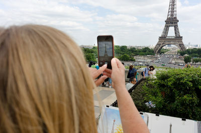 Rear view of woman photographing eiffel tower