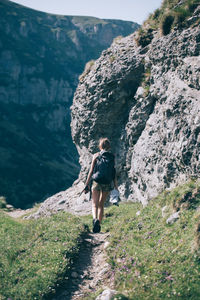 Rear view full length of female hiker walking on mountain