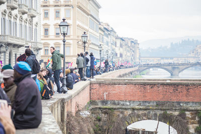 People on bridge over canal in city