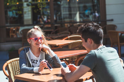 Young man and woman sitting on table at cafe