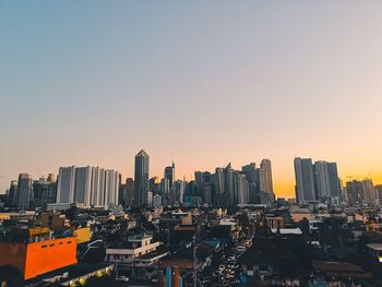 Modern buildings in city against clear sky during sunset