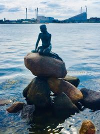 Statue of rocks by sea against sky