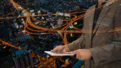 Digital composite image of businessman using digital tablet with cityscape