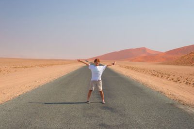 View of woman standing in desert against clear sky
