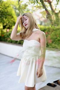 Portrait of young woman standing against trees