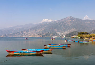 Boats moored in sea against mountains