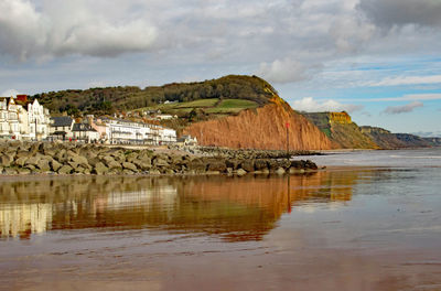 Scenic view of sea by buildings against sky