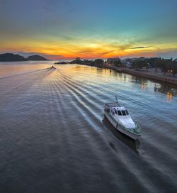 Boats moored on river against sky during sunset