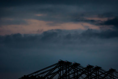 Silhouette crane against sky at dusk
