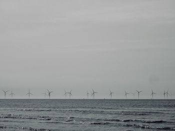 Windmills in sea against sky