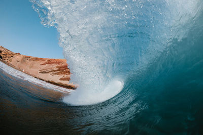 Blue wave breaking front a red mountain in tenerife