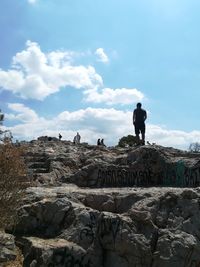 Rear view of man standing on rock against sky