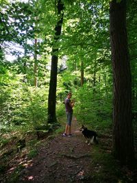 Teenage girl with dog walking in forest