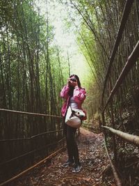 Woman standing by railing in forest