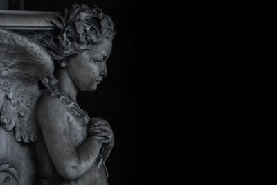 Side view of young woman against black background