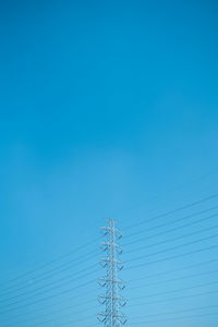 Low angle view of electricity pylon against blue sky