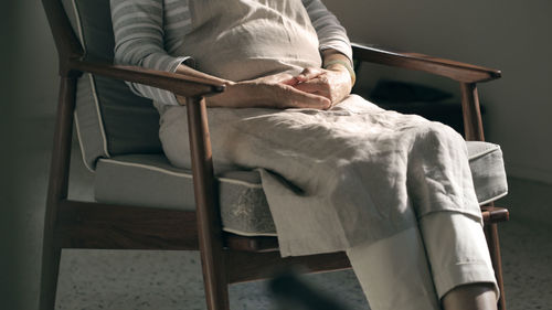 Midsection of person sitting on chair