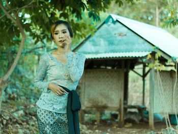 Young woman looking away while standing against trees