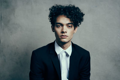 Portrait of young man sitting against wall