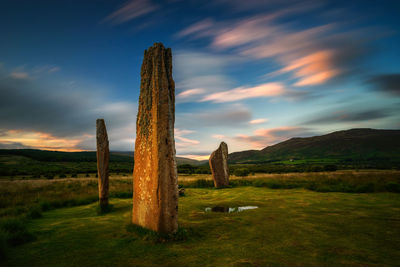 Wooden posts on field against sky during sunset