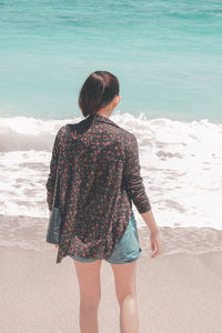 Rear view of woman standing on beach