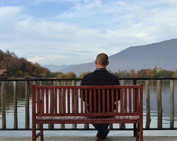 Rear view of man on railing against sky