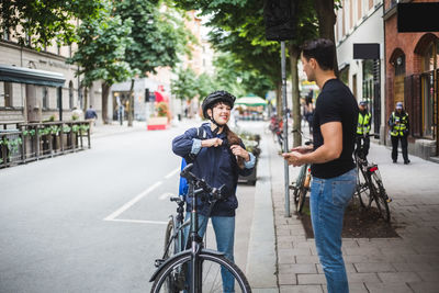 Delivery woman talking with male customer standing on sidewalk in city