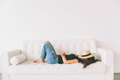 Side view of young woman lying on sofa at home