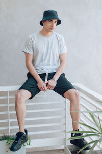 Young man sitting against wall