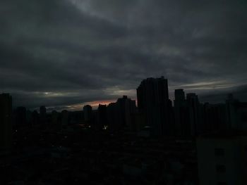 Cityscape against cloudy sky at sunset