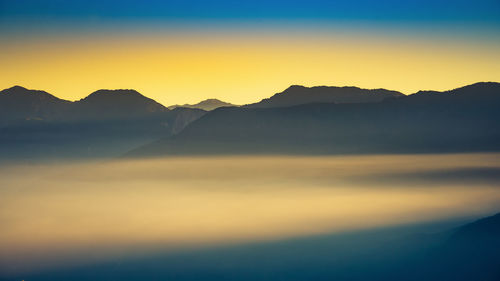 Scenic view of silhouette mountains against romantic sky at sunset