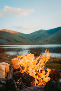 High angle view of bonfire on mountain by lake against sky