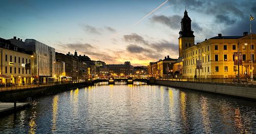 Canal amidst buildings against sky during sunset