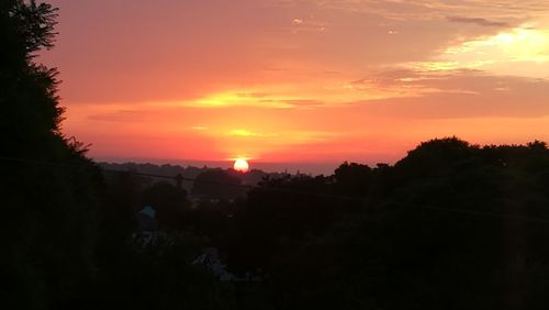 Scenic view of silhouette landscape against orange sky