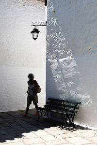 Full length of woman standing on footpath against wall