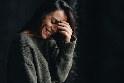 Portrait of a smiling young woman against black background