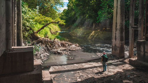 High angle view of young man standing below bridge by river