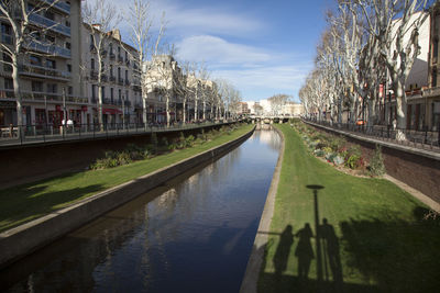 Canal amidst buildings in city against sky