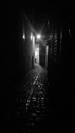 Empty narrow alley along buildings at night