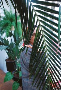 Portrait of young woman standing against plants