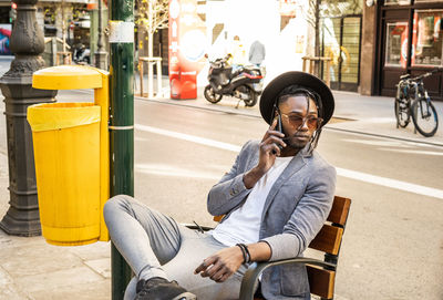 Full length of man sitting on street in city