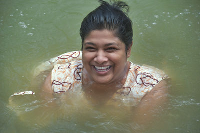 Portrait of smiling young woman swimming in lake