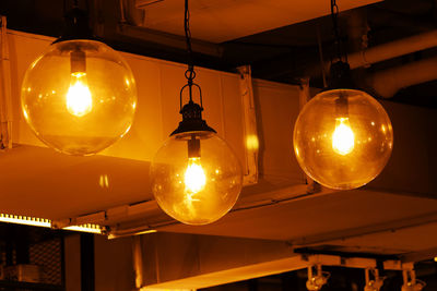 Low angle view of illuminated pendant light hanging from ceiling