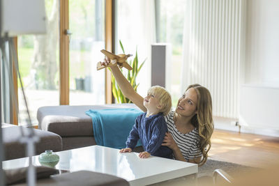 Mother and son playing with toy plane in living room