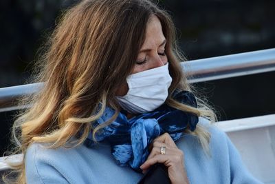 Close-up of woman wearing mask sitting outdoors