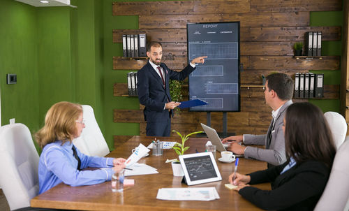 Businessman giving presentation to colleagues in meeting room at office