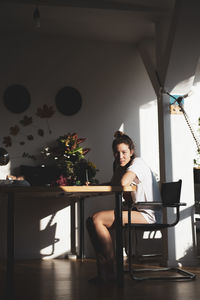 Beautiful natural young woman sits and writes smiling in warm sunlight