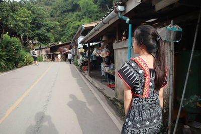 Rear view of woman walking on road in city