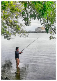 Rear view of man fishing in river